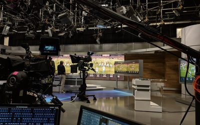 Uno studio televisivo con le telecamere puntate e la partita di calcio sui monitor