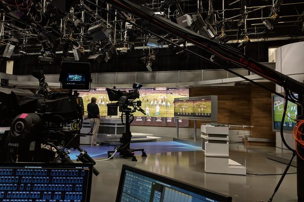 Uno studio televisivo con le telecamere puntate e la partita di calcio sui monitor